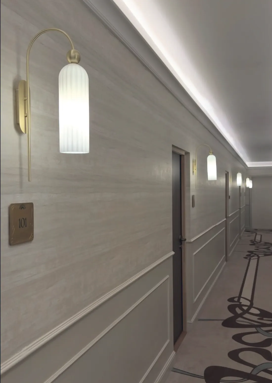 Couloir de l’hôtel, applique dorée et plaque de chambre