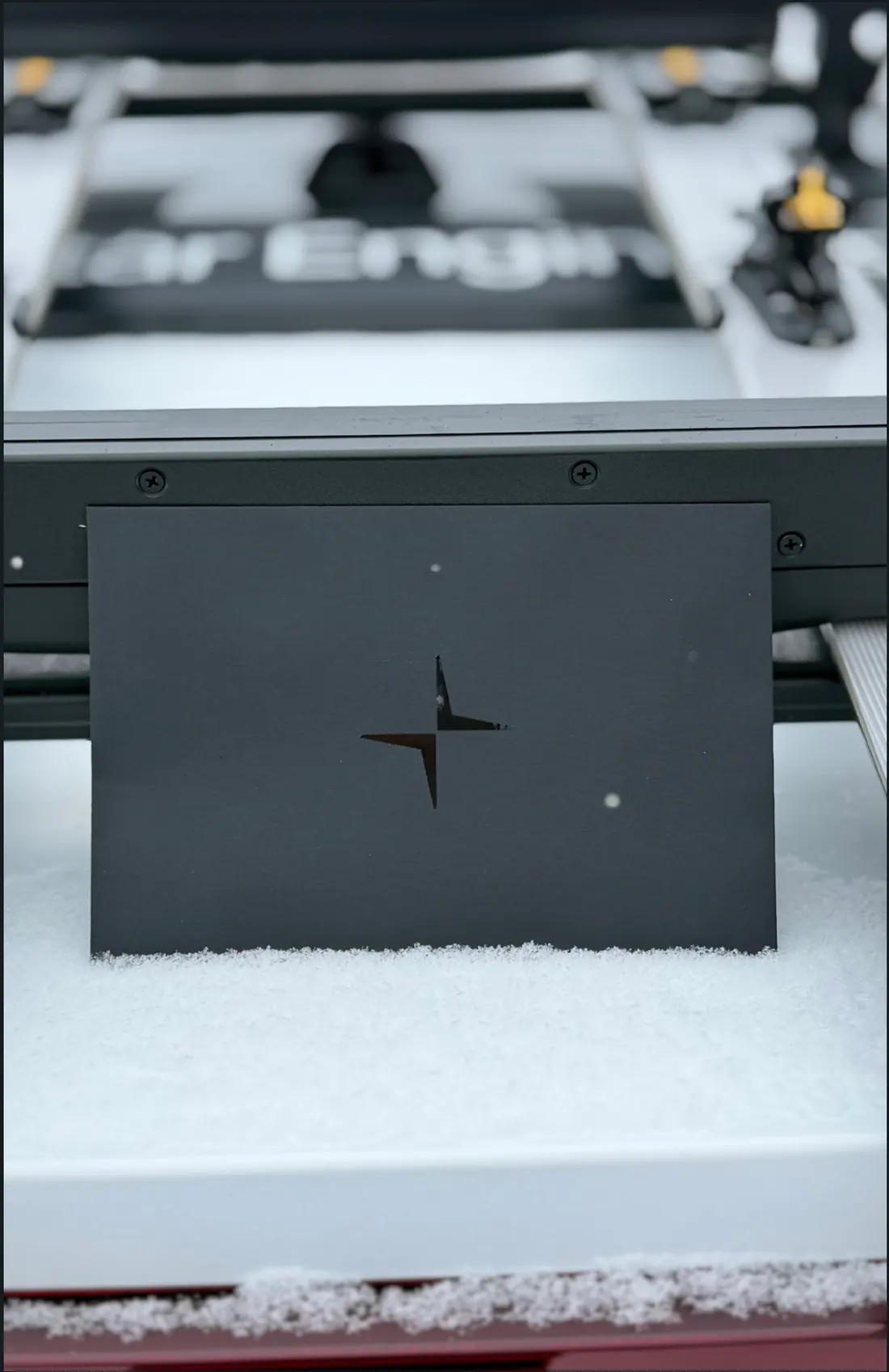 Carton noir découpé au logo Polestar, posé dans la neige
